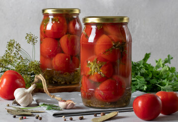 Marinated tomatoes with cilantro in jars for the winter on gray background