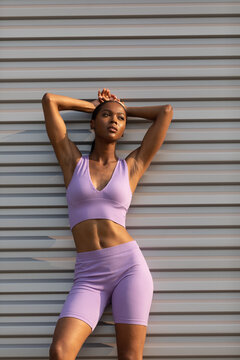 African-American Woman Resting In Purple Fitness Apparel Against Grey Steel Background Vertical Image _0079