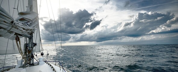 White yacht sailing in an open sea on a summer day. Close-up view from the deck to the bow and...