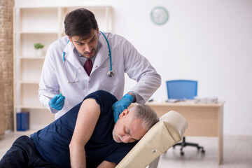 Fototapeta premium Old male patient visiting young male doctor in vaccination conce