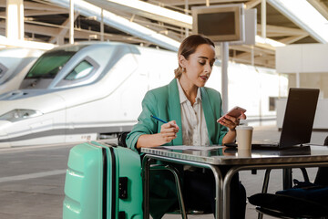 Woman about to travel. Working at the station waiting for her train. Concept entrepreneurial women, business travel.