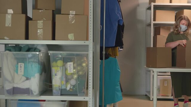 Creative team of fashion designers in safety mask preparing products to deliver to customers