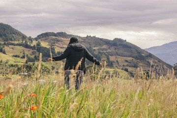 Chica  joven abriendo los brazos en paisaje de campo con sol por la espalda