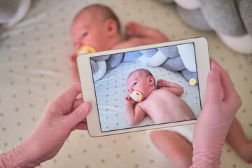 The doctor takes a video on a tablet with a newborn baby. A nurse conducts an online consultation on the treatment of a child