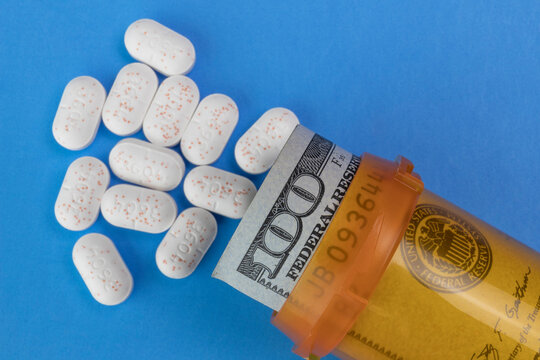 Hydrocodone tablets with a hundred dollar bill and a pill bottle. Opiate addiction costs the U.S. economy $78.5 billion per year.