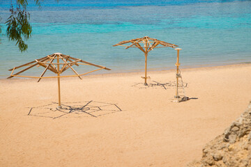 Empty beach with no people during a pandemic. Azure and turquoise sea water. Abandoned wooden umbrella frames. Free space.