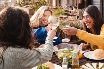Multiracial friends eating vegan food cheering with wine outdoors at patio restaurant - Focus on...