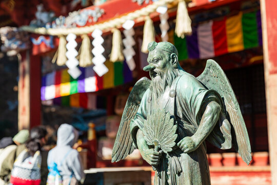 statue of long-nosed goblin "tengu" and japanese prayers in front of the temple of takao mauntain in tokyo, japan