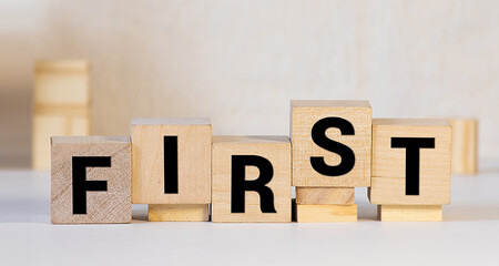 word first written with black letters on small wooden blocks against bright yellow background at light closeup