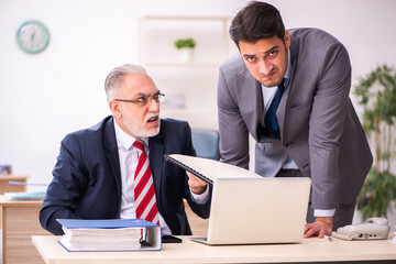 Old boss and young male employee working in the office