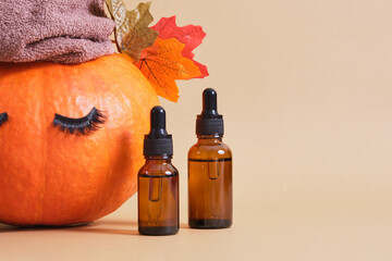mock up cosmetic containers with pipettes and pumpkin with towel and eyelashes on beige background,...