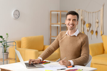 Young male calligrapher using laptop in office