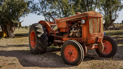 old rundown orange tractor parked outdoors.