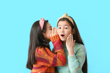 Cute little girls telling secrets to each other on color background - obrazy, fototapety, plakaty