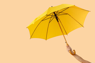 Female hand with open umbrella on color background © Pixel-Shot
