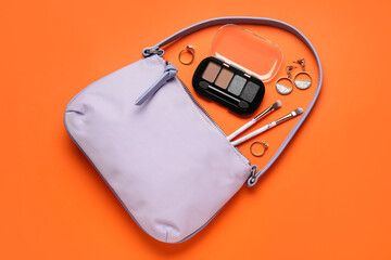 Stylish handbag, eyeshadows and different accessories on color background