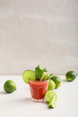 Glass of bloody mary cocktail and limes on table
