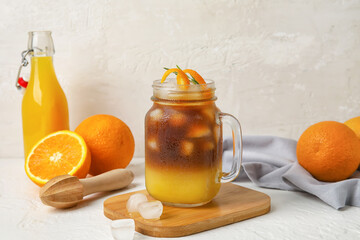 Mason jar of tasty coffee with orange juice on light background