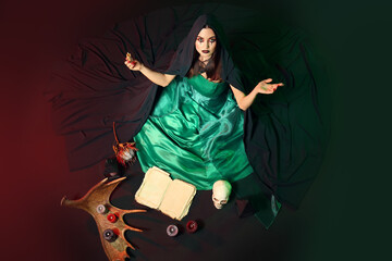 Young witch performing ritual on dark background