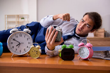 Young male employee sleeping in the office in time management co