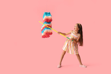 Little girl breaking Mexican pinata on color background
