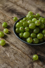 Bowl with fresh ripe gooseberry on wooden background