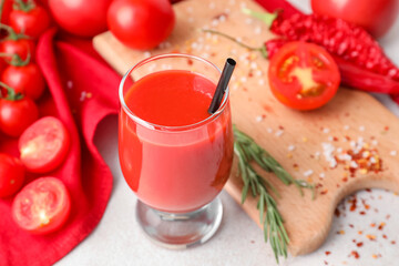 Glass of tasty tomato juice on light background