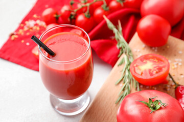Glass of tasty tomato juice on light background