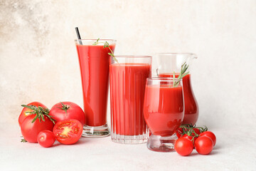 Glasses of tasty tomato juice on light background