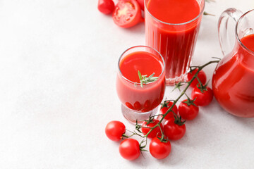 Glasses of tasty tomato juice on light background