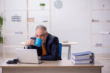 Fototapeta premium Old male employee drinking coffee during break