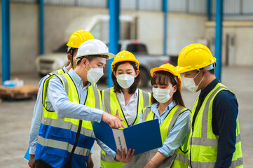 The factory employee consists of engineers, foreman, technicians, and related department staff. Wear a mask, hard hat, and vest. meeting before starting work inside the warehouse. Teamwork concept.