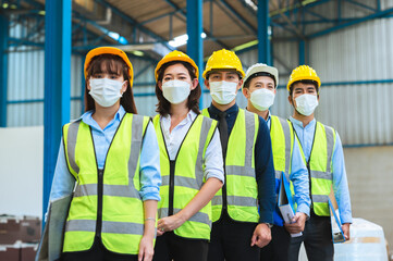 The factory employee consists of engineers, foreman, technicians, and related department staff. Wear a mask, hard hat, and vest. meeting before starting work inside the warehouse. Teamwork concept.