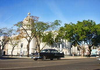 Classic auto drives past the Capitolio building, Havana, Cuba.