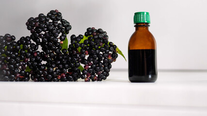 Herbal tincture of black berries, medicinal elderberry on a white background.