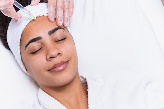 Plastic surgery. Young african woman receiving botox injection in interbrow zone at beauty clinic, closeup, copy space. Young African woman getting Botox injection in her forehead..