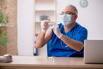 Old male doctor in vaccination concept
