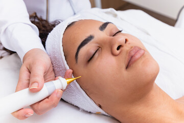 Woman doing facial treatment with plasma jet in beauty clinic.