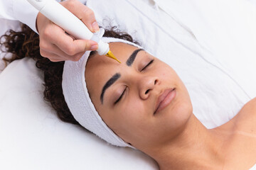 Woman doing facial treatment with plasma jet in beauty clinic.