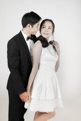 Young attractive Asian couple, bride and groom, woman wearing white wedding dress. Man wearing black tuxedo, standing together. Concept for pre wedding photography