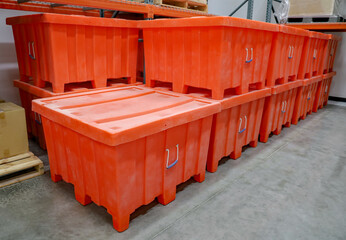 Large orange bulk containers with lids at a warehouse.