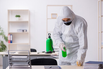 Young male contractor disinfecting office during pandemic