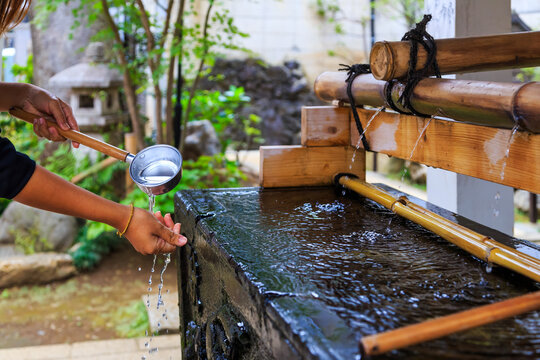 Unidentified Japanese people washing hand at bamboo fountain before giving the worship at the shrine.