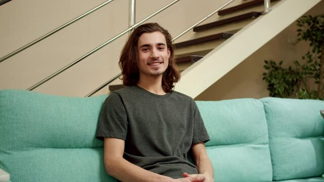 A young man is looking to the camera and smiling 