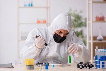 Young male chemist working at the lab during pandemic