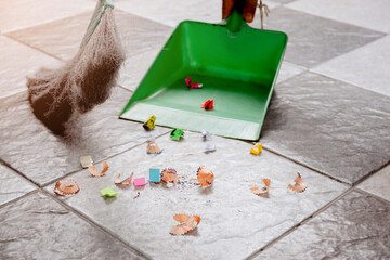 Sweep up scraps of paper and dust on tile floors with a broom and a plastic dustpan.