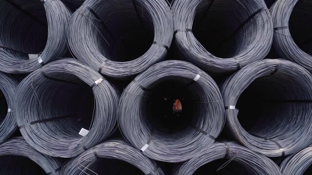 Black metal coils piles, outside at the Goa Port in cloudy India - dolly view