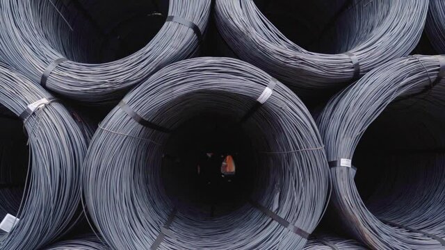Steel wire rolls, piled up in large rows, at a ironworks, in India - pull back, drone shot