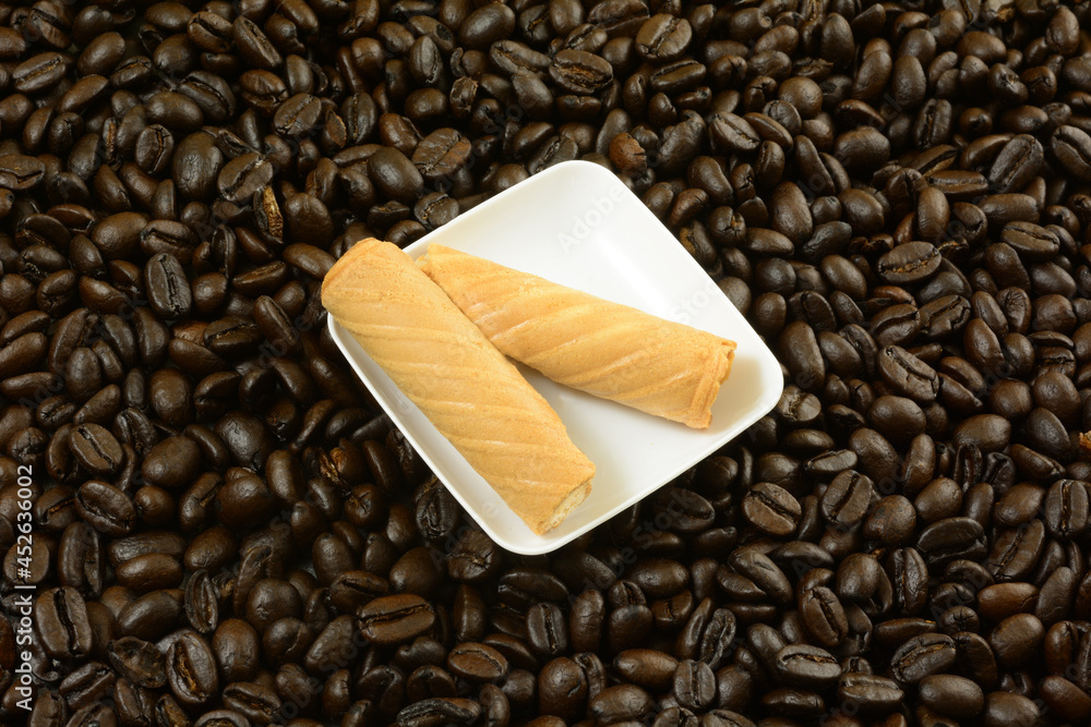 Wall mural coffee cream wafer roll cookies on white snack plate on coffee beans