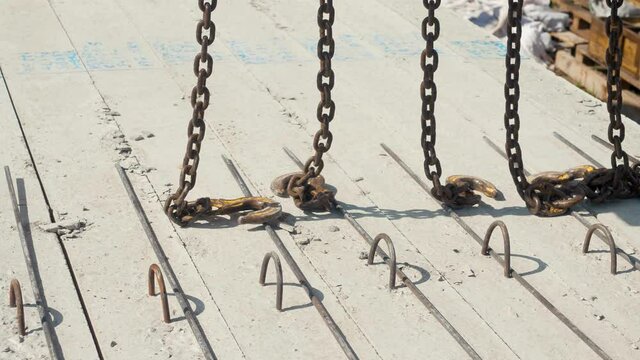 A worker removes hooks from concrete pillars that have been loaded onto a machine.